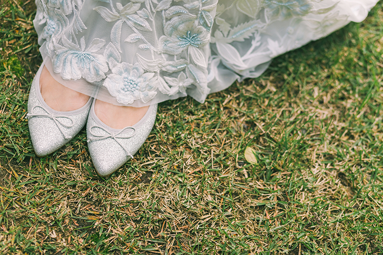 レースが美しいウェディングドレスの裾から覗く繊細なラメが上品に光るポインテッドトゥバレエシューズ