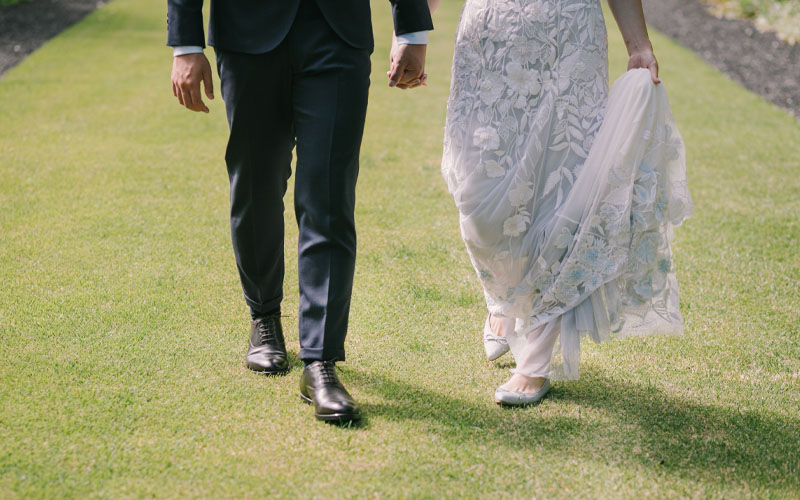 裾のレースが美しいウェディングドレスに繊細なラメが上品に光るポポインテッドトゥバレエシューズを履いた花嫁と新郎