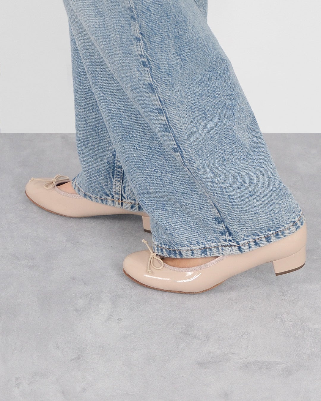ライトブルーのストレートデニムパンツに合わせた3cmヒールバレエ(エナメル)のベージュ。肌なじみの良いエナメルパンプスの足元側面ショット。