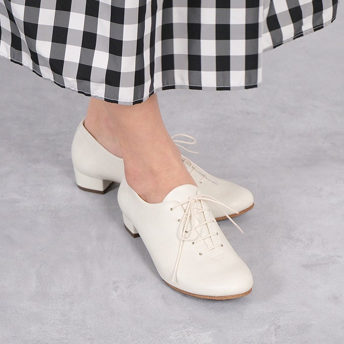 ミドルヒールが上品な品格を添えるシンプルなホワイトのレースアップシューズとギンガムチェックスカートのスタイリング。