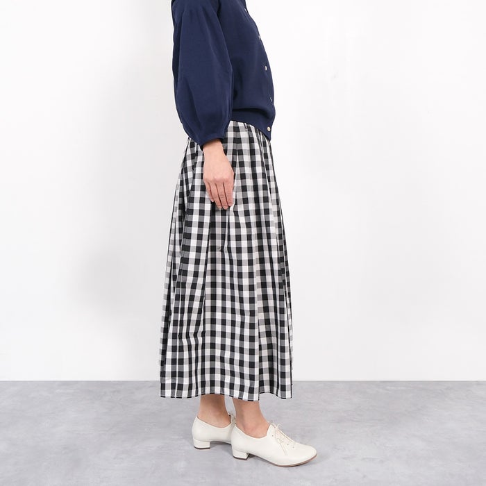 軽やかなホワイトのミドルヒールレースアップシューズとガーリーなギンガムチェックのスカートの甘さを抑えた大人が楽しめるシンプルなスタイリング。