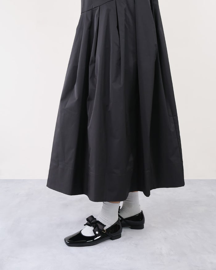 黒のフレアフレアスカートとシルバーソックスにリボン付きブラックエナメルストラップパンプスを合わせた下半身側面アングル。
